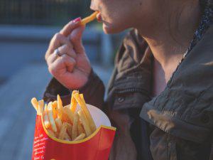 Salud Ecológica: Mujer comiendo fast food, un alimento basura